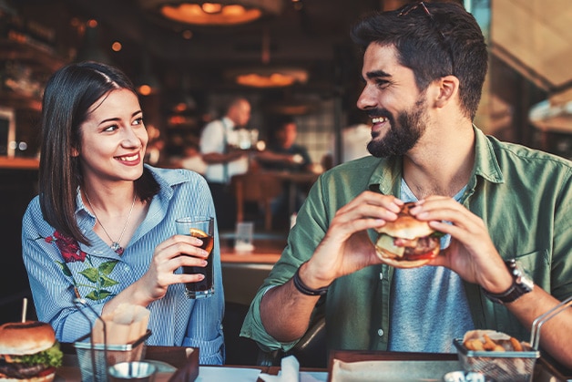 pareja comiendo hamburguesa y tomando gaseosa