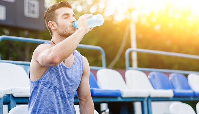 Hombre bebiendo agua con los ojos cerrados luego de ejercicios