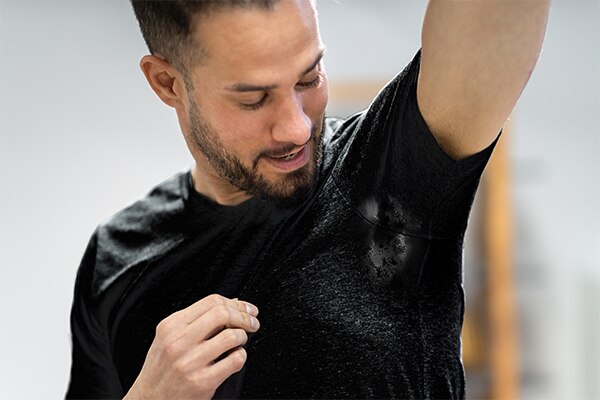 Hombre oservando su camisa sudorosa